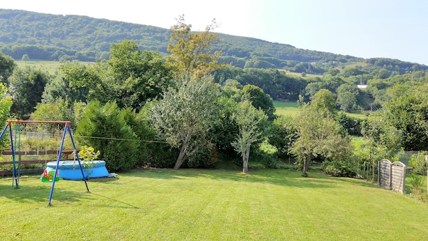 A grassy yard with a swing set and a blue play structure. - Cozy Chalet Escape in the Alps (Saint-Jean-de-Vaulx)