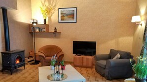 A living room with a fireplace, a sofa, a television, and a coffee table. - Cozy Chalet Escape in the Alps (Saint-Jean-de-Vaulx)