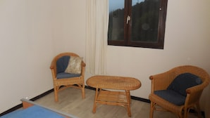 A small room with two wicker chairs, one with a cushion and another with a pillow, a small wooden table, and a window with a view of the outside. - Cozy Chalet Escape in the Alps (Saint-Jean-de-Vaulx)