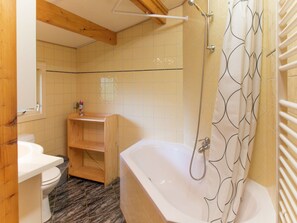 Ein Badezimmer mit Badewanne, Toilette und Holzregalen.
