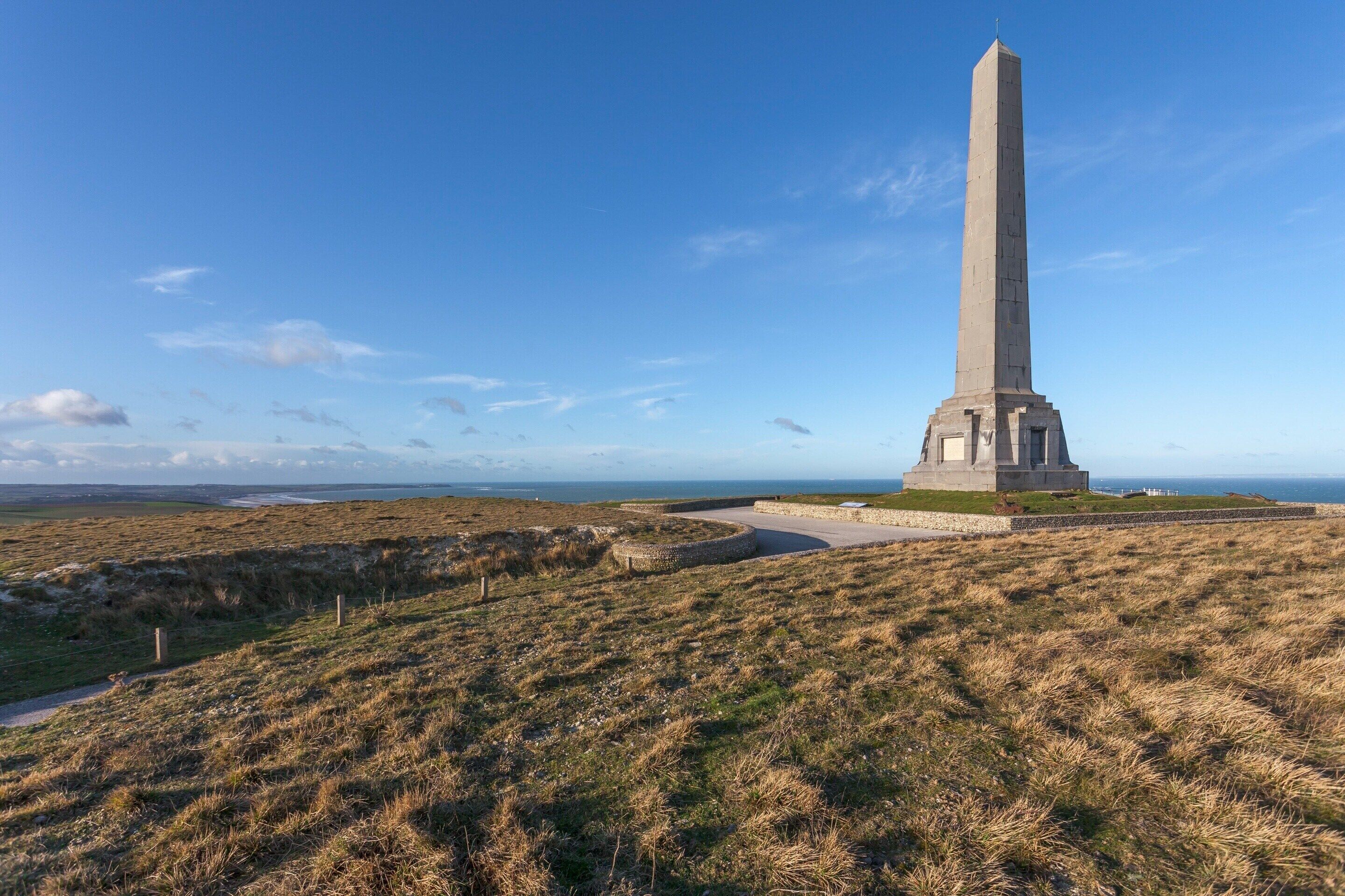 A tall monument on a grassy hill with a clear sky.