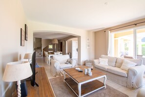 A living room with a sofa, a coffee table, a lamp, and a television. - Holiday Home in Le Plan-de-la-tour With Pool (Plan-de-la-Tour)