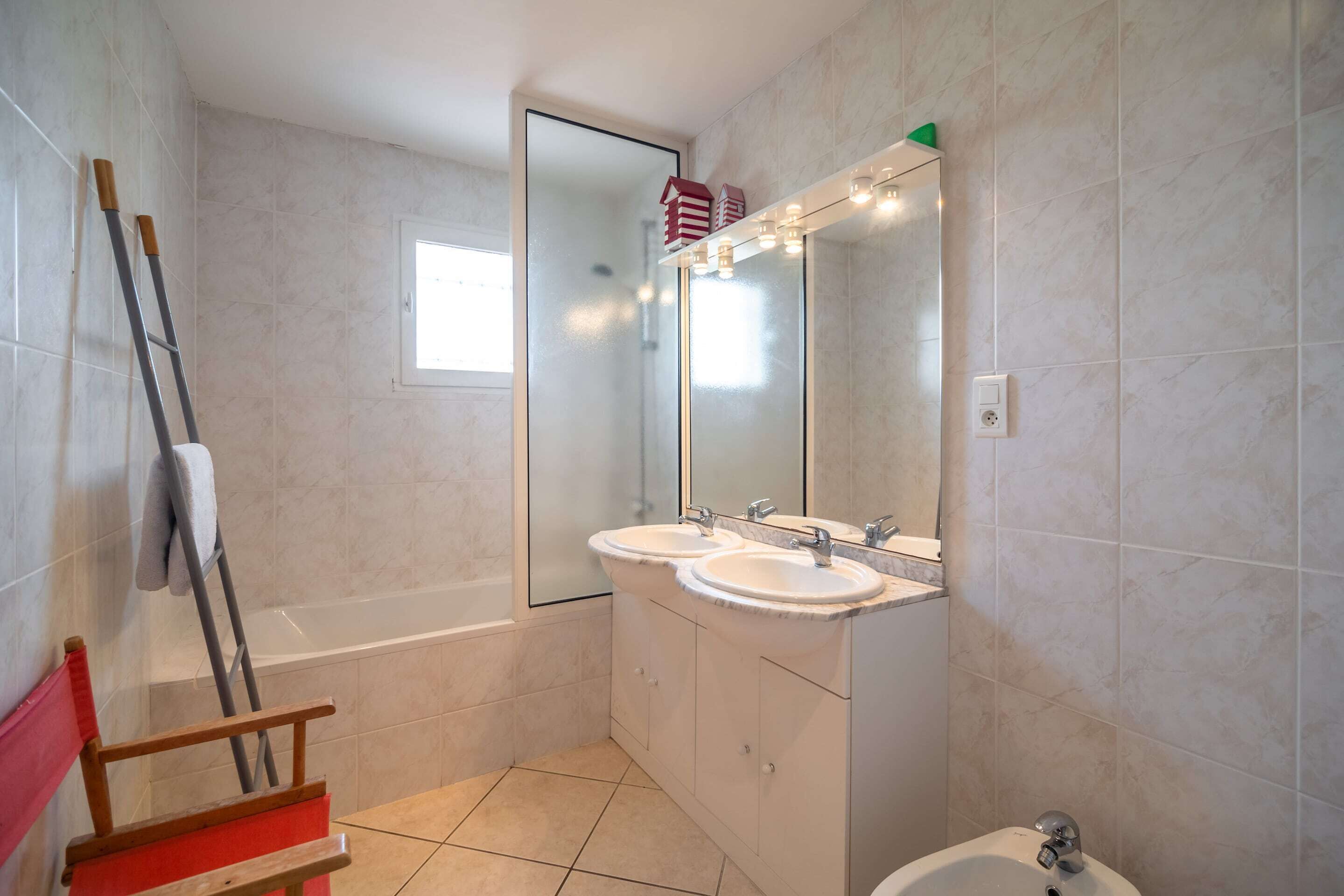 A bathroom with two sinks, a mirror, a bathtub, and a shower.