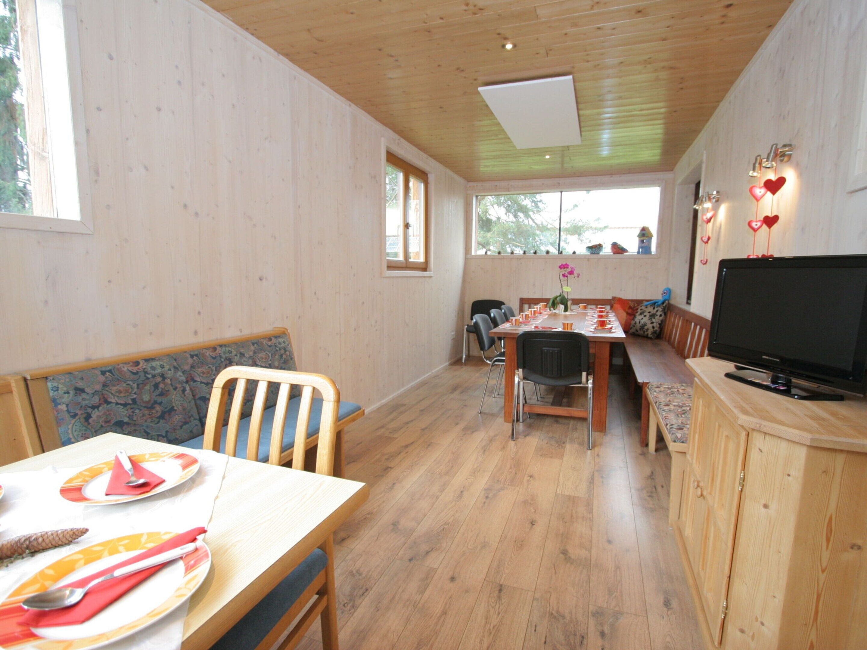 A cozy dining area with wooden furniture, a television, and heart-shaped wall decorations.