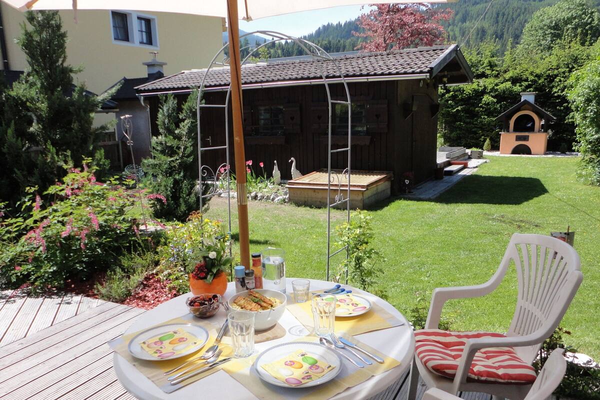 A dining table set outdoors with plates, cutlery, and glasses.