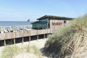 A beachside restaurant with a wooden deck and a view of the ocean.