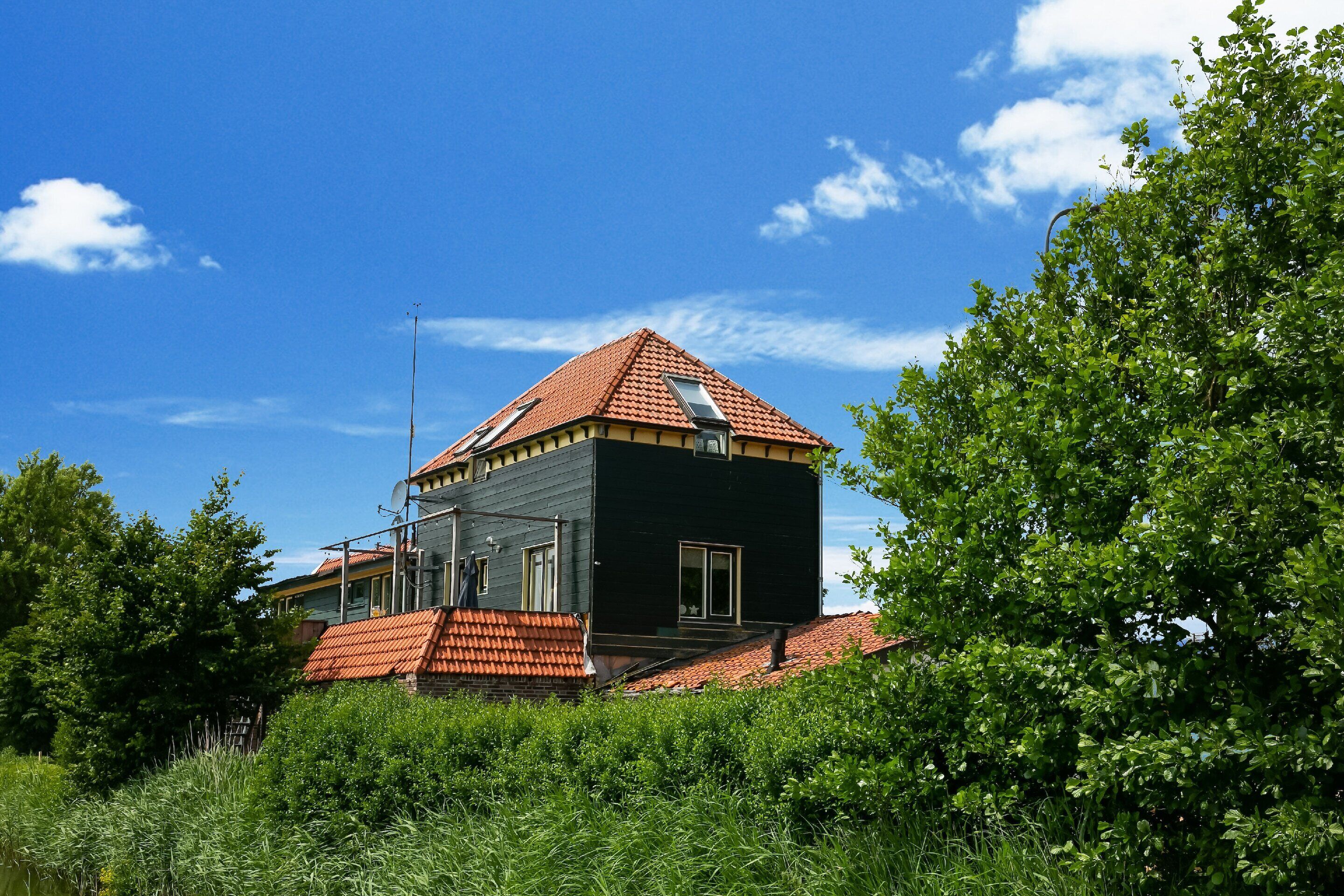 A modern house with a red-tiled roof, a satellite dish, and a small balcony.