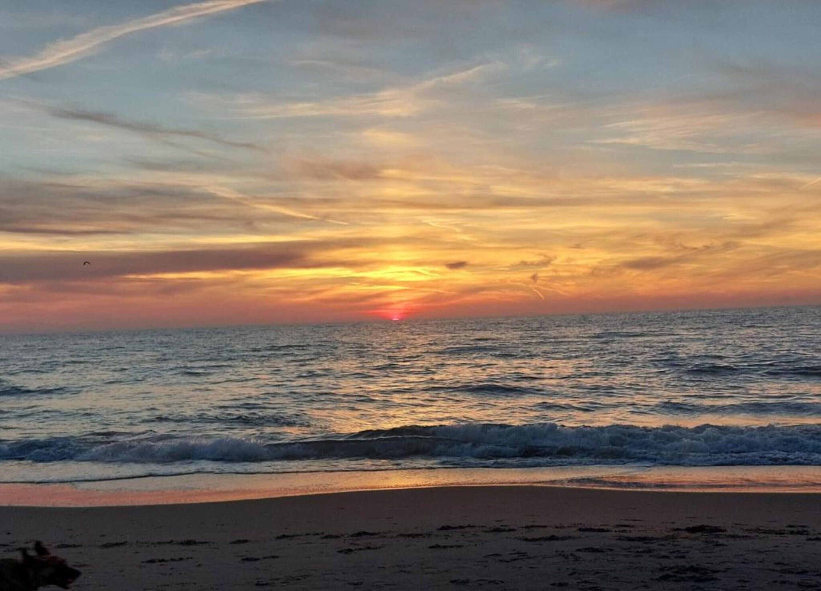 Ein Strand mit Wellen und einem Sonnenuntergang.