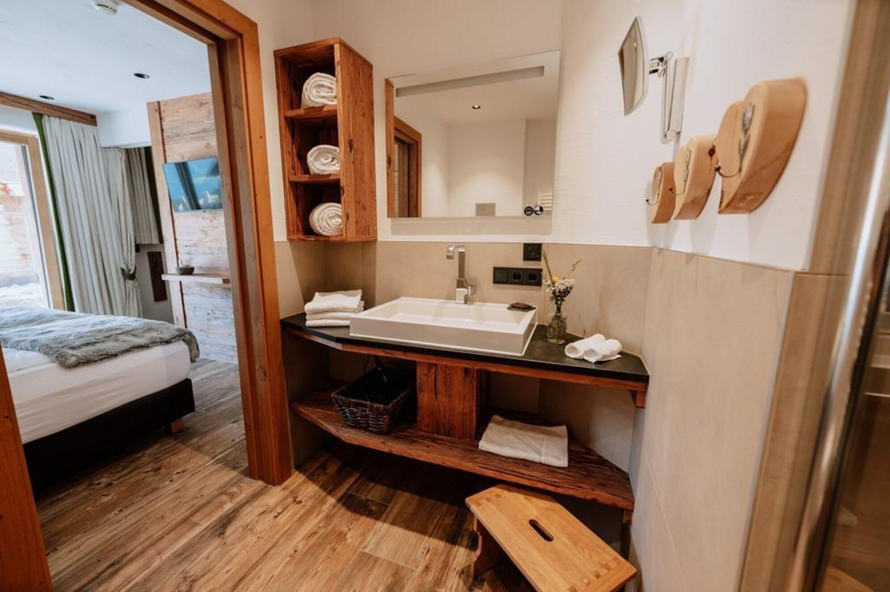 Un baño moderno con un lavamanos grande, repisas de madera, un espejo y un banco.