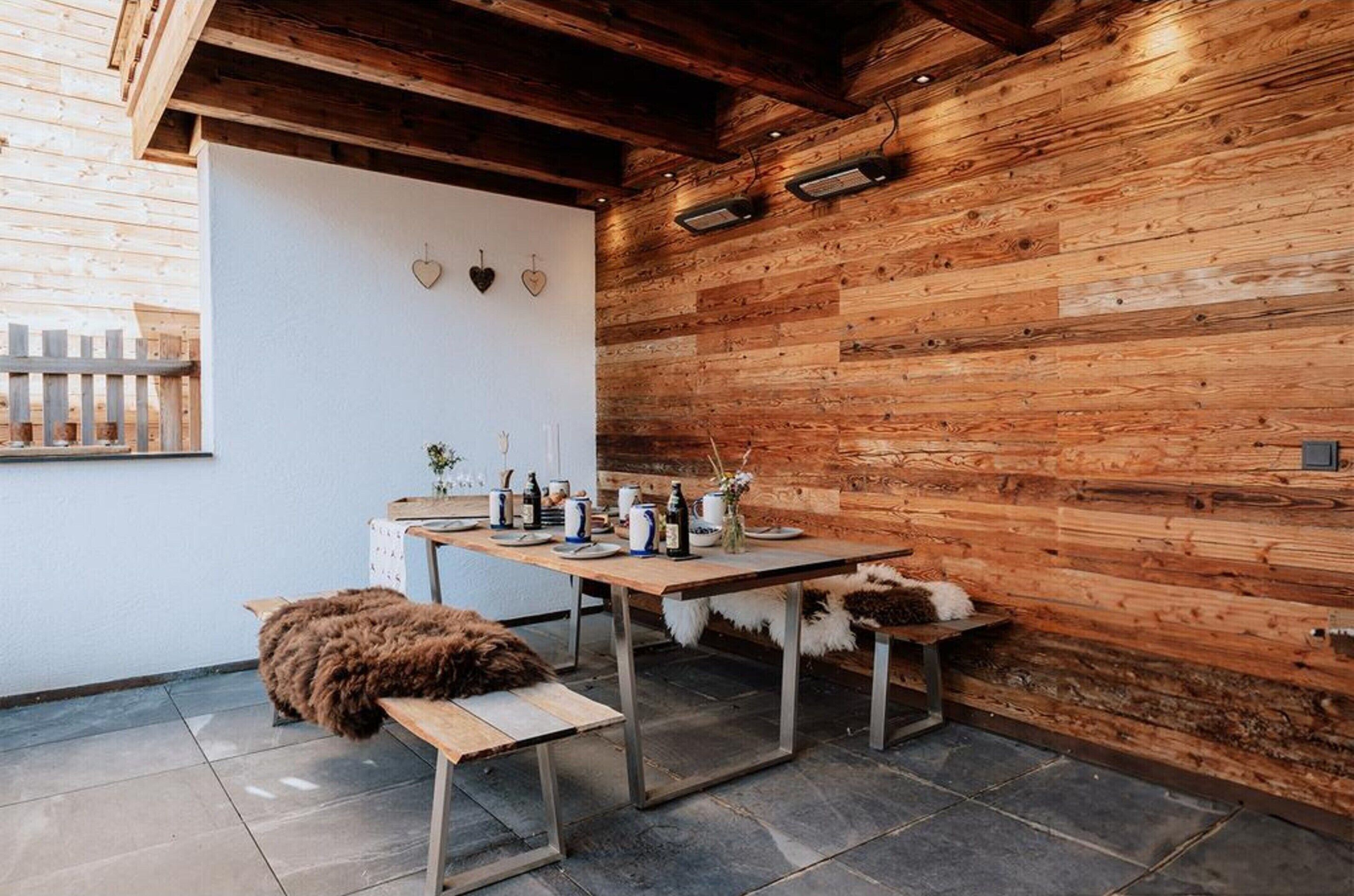 Een rustiek houten interieur met een eettafel voor vier personen, een bank en een pluizige bruine hond.
