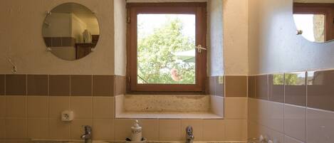 A bathroom with two sinks, a window, and a mirror.