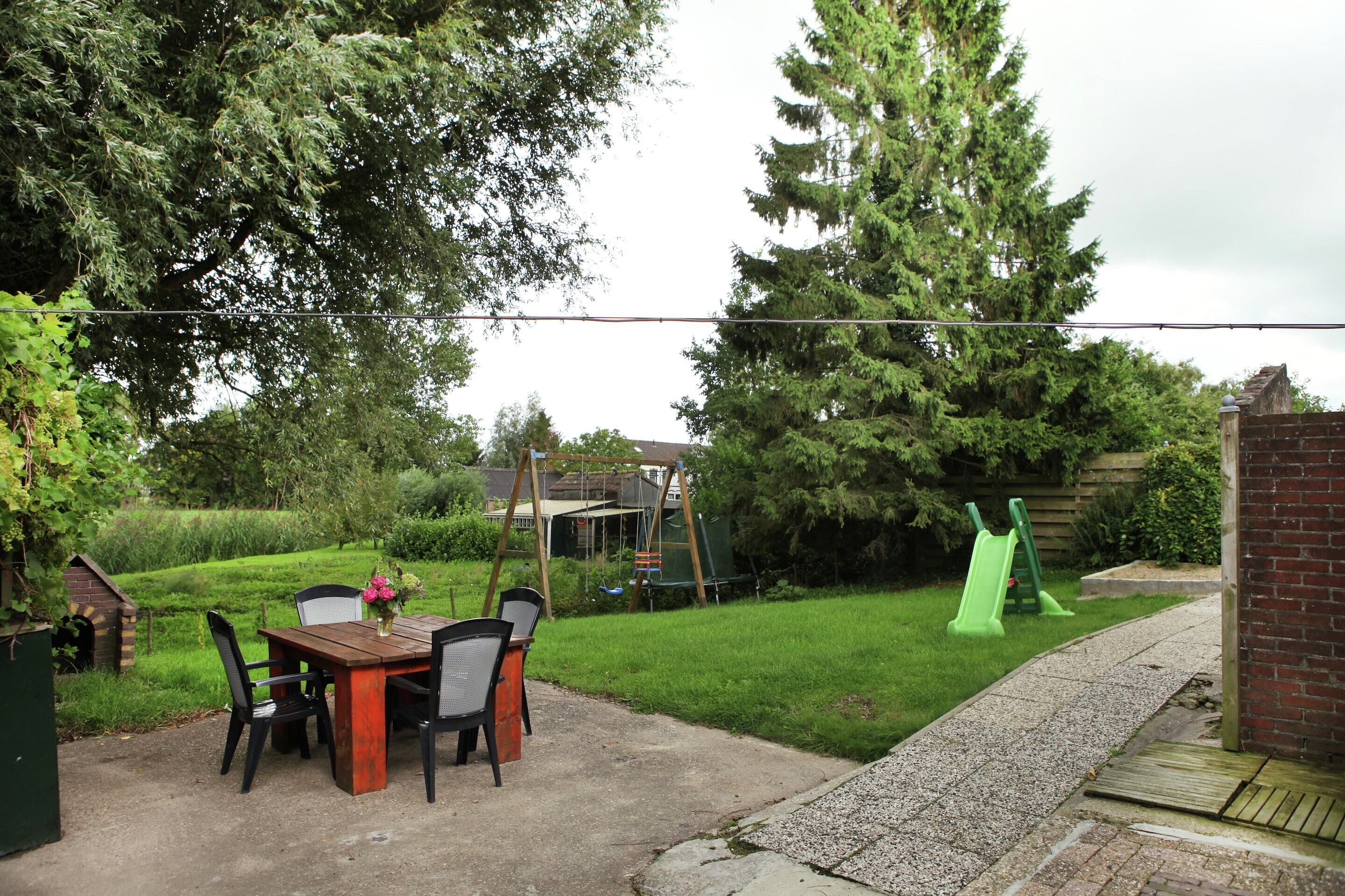 A patio with a table and chairs, a brick wall, and a green slide.