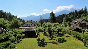 Et boligområde med huse omgivet af frodig vegetation og bjerge i baggrunden.