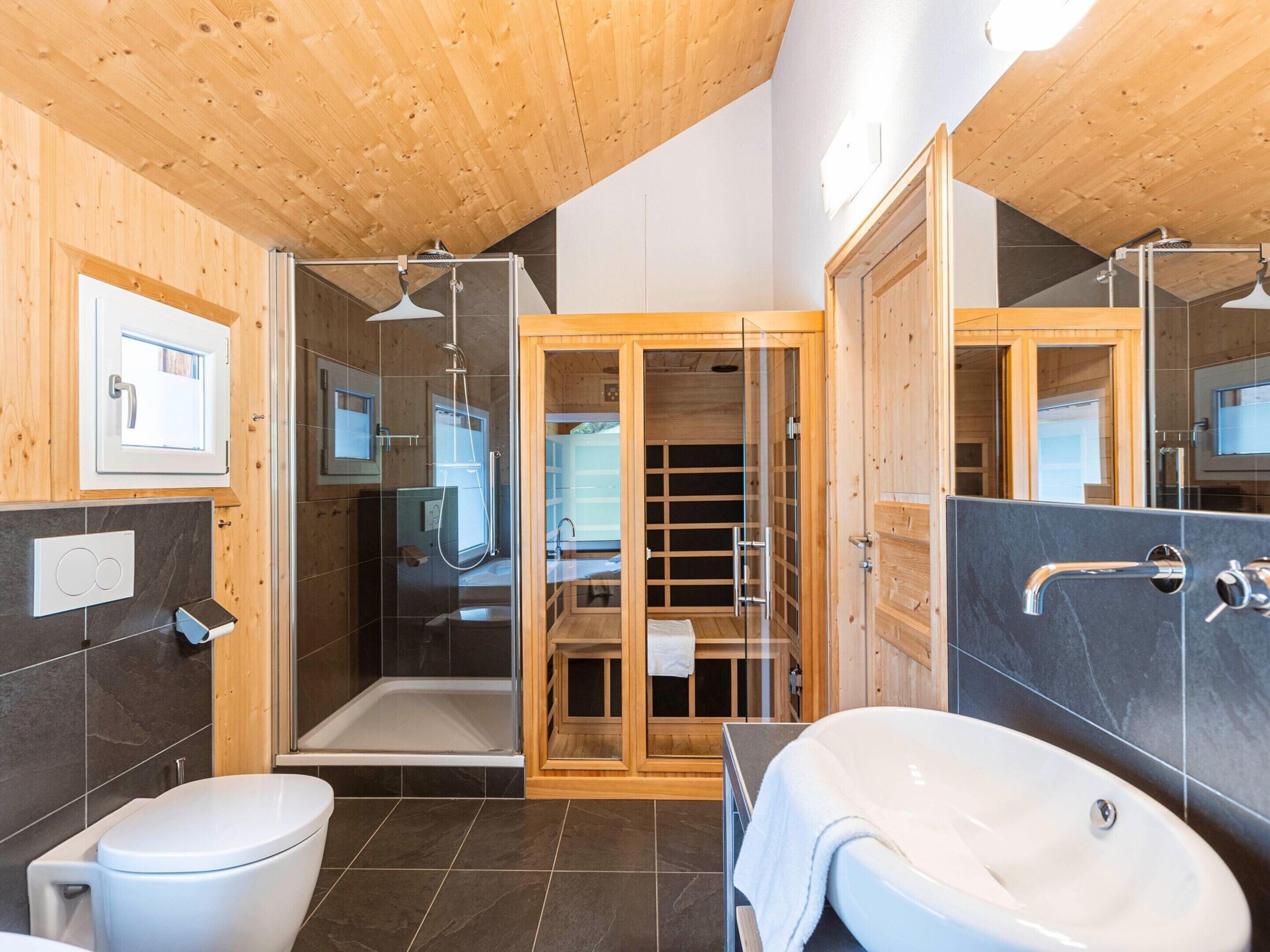 A modern bathroom with a wooden ceiling, a glass shower enclosure, a white toilet, and a white sink.