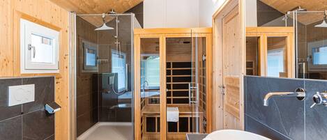 A modern bathroom with a wooden ceiling, a glass shower enclosure, a white toilet, and a white sink.
