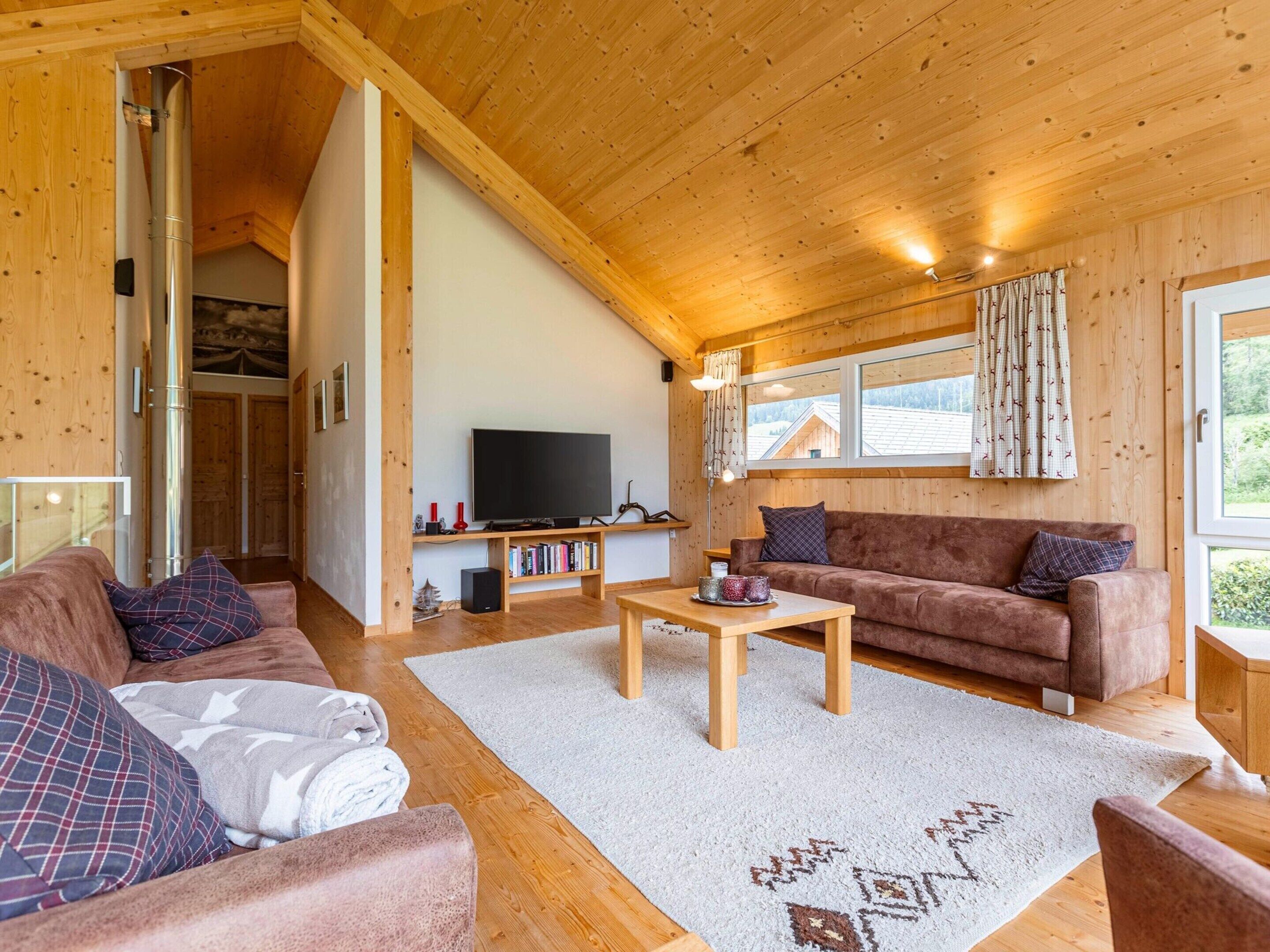 A cozy wooden interior with a sofa, a TV, and a bookshelf.