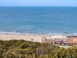 Una playa con arena, algunas personas y un edificio con techo rojo al frente.