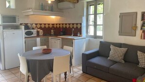 Cocina compacta con una mesa de comedor, un sofá y un ventanal.