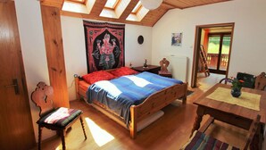 Un dormitorio acogedor con una cama de madera, una silla, una mesa y un tapiz en la pared.