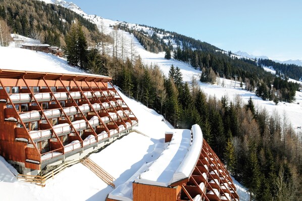 A ski resort with wooden cabins and a snow-covered mountain backdrop. - Apartment in French Alps Near Ski Slopes (Bourg-Saint-Maurice)