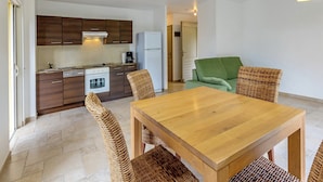 Una cocina moderna con armarios de madera oscura, un refrigerador blanco y un comedor con mesa de madera y sillas de mimbre.