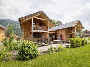 Un chalet en bois doté d’un balcon et d’un jacuzzi dans la cour.