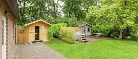 A brick building with a wooden door and a small wooden structure in the yard.