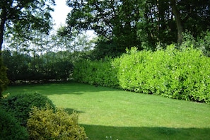 A well-maintained garden with a neatly trimmed lawn, dense shrubbery, and tall trees providing shade. - Kempen Comfort With Sauna & Tub (Vessem)