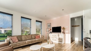 Uma sala de estar moderna com um sofá, duas mesas de centro e uma televisão sobre um móvel.