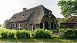 A traditional brick house with a steeply pitched thatched roof, a brick chimney, and a small garden with hedges. - Farmhouse in Rheeze Near Forest and Meadows (Rheeze)