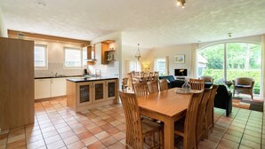 A spacious kitchen with a large dining table and chairs, a built-in island, and a view of the garden through large windows. - Farmhouse in Rheeze Near Forest and Meadows (Rheeze)