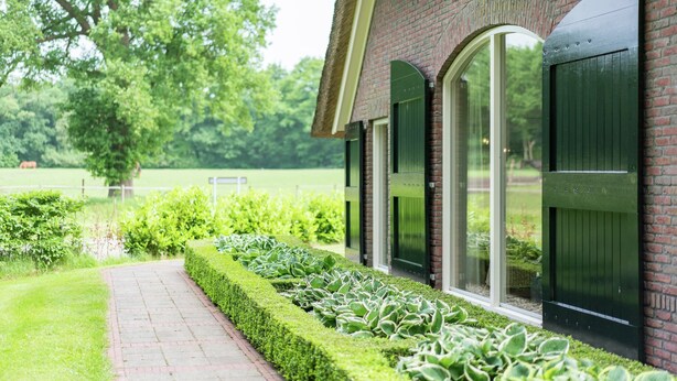A brick building with arched windows and a pathway leading to a green lawn. - Farmhouse in Rheeze Near Forest and Meadows (Rheeze)