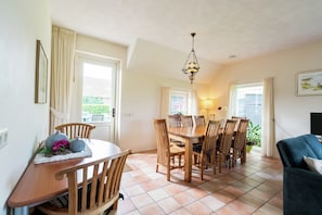 A dining area with a wooden table and chairs, a chandelier, and a view through the windows. - Farmhouse in Rheeze Near Forest and Meadows (Rheeze)