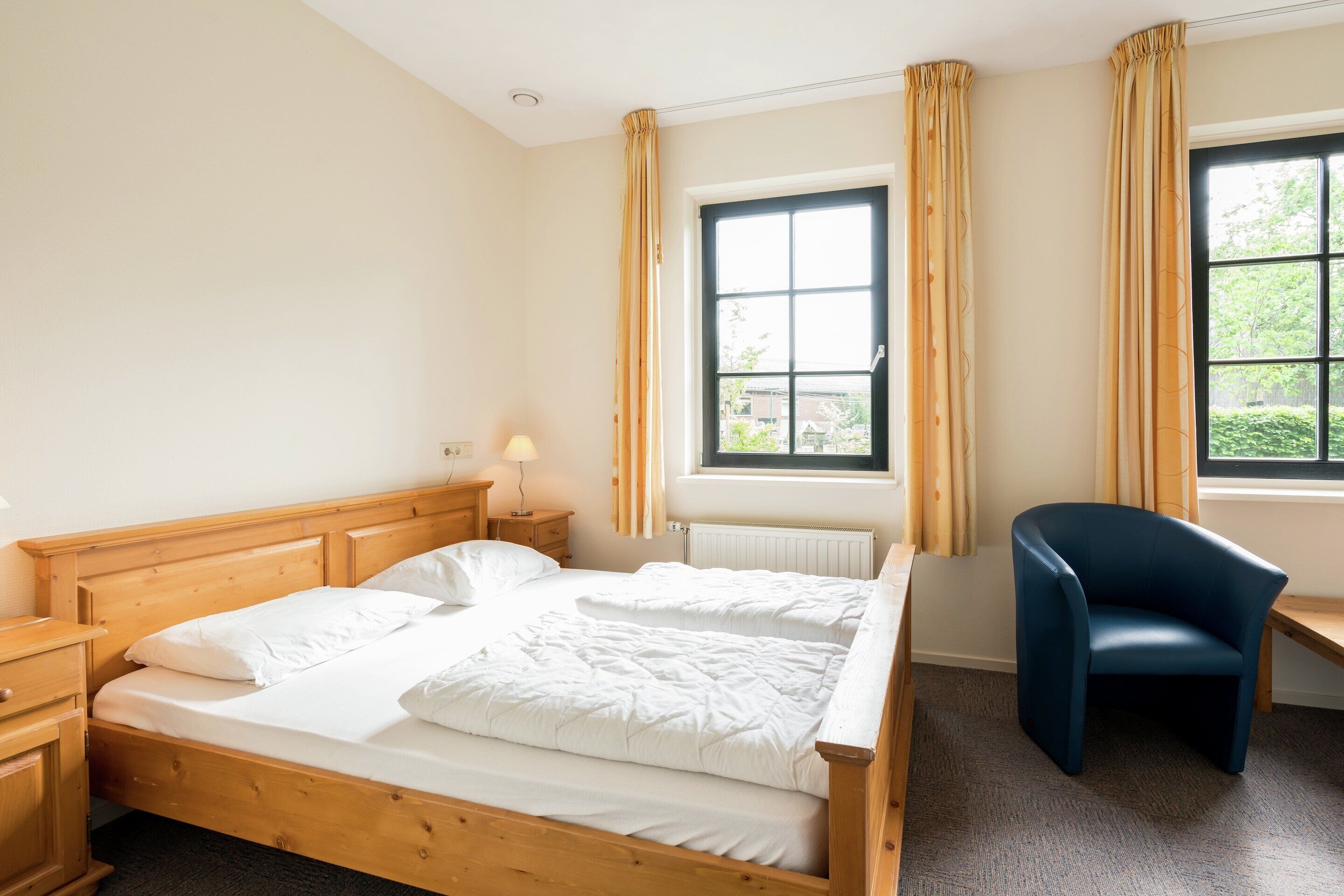 A bedroom with a wooden bed, a desk, and a chair.