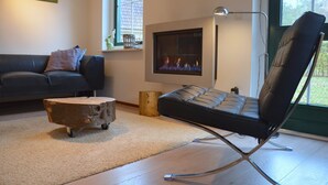 A modern living room with a fireplace, a sofa, a coffee table, and a chair. - Holiday Home in Heeten Near Forest (Heeten)