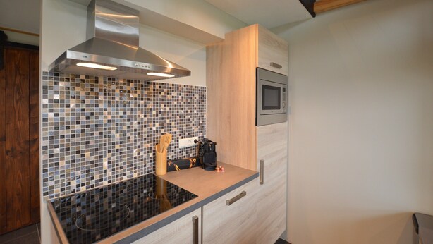 A modern kitchen with a stainless steel range hood, a microwave, and a tiled backsplash. - Tranquil Holiday Home in Alphen-chaam With Stables (Alphen)