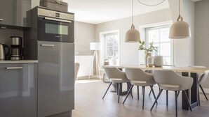 Una cucina moderna con un forno Bosch, una macchina da caffè e un'area pranzo con un tavolo di legno e sedie bianche.