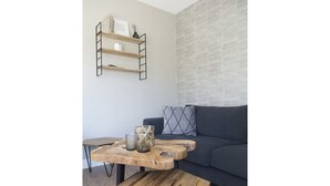 Un soggiorno con un divano grigio scuro, un tavolino in legno con un candelabro in vetro e una mensola a parete con oggetti decorativi.