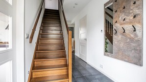 A wooden staircase with a handrail, leading to a landing with a white door and a wall-mounted mirror. - Modern Villa in Harderwijk with Hot Tub (Zeewolde)