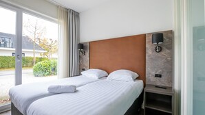 A double bed with white linens, a wooden headboard, and two bedside tables with lamps. - Modern Villa in Harderwijk with Hot Tub (Zeewolde)