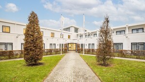 A modern building with a central entrance, a reception area, and a paved walkway. - Modern Villa in Harderwijk with Hot Tub (Zeewolde)