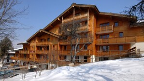 A multi-story wooden building with balconies, surrounded by snow. - Cozy Chalet Stay w/ Pool (Notre-Dame-de-Bellecombe)