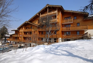 Un immeuble en bois à plusieurs étages, doté de balcons, et entouré de neige.