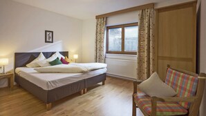 A bedroom with a bed, bedside tables, a chair, a window, and a radiator. - Residence in Kaltenbach Near ski Lifts (Kaltenbach)