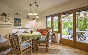 A dining area with a round table, chairs, and a view of the outdoors through large windows. - Residence in Kaltenbach Near ski Lifts (Kaltenbach)