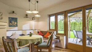 A cozy dining area with a round table, wooden chairs, and a bench. There are two windows providing a view of the outdoors. - Residence in Kaltenbach Near ski Lifts (Kaltenbach)