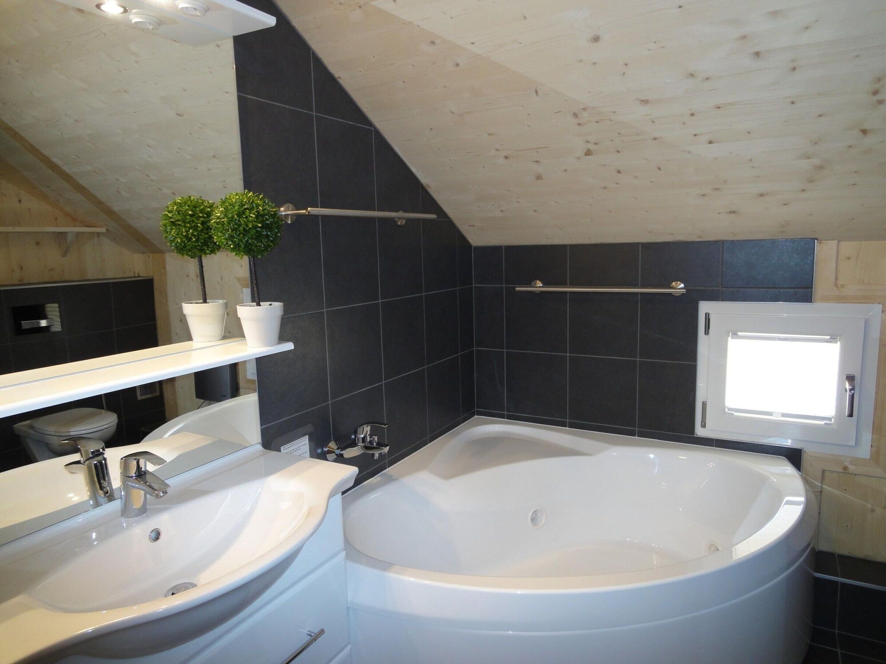 A bathroom with two sinks, a bathtub, a potted plant, a mirror, and a towel rack.