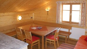A cozy wooden cabin with a dining table, chairs, and a window with curtains.