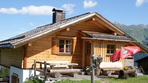 A wooden lodge with a sloped roof, a chimney, and a wooden bench outside.
