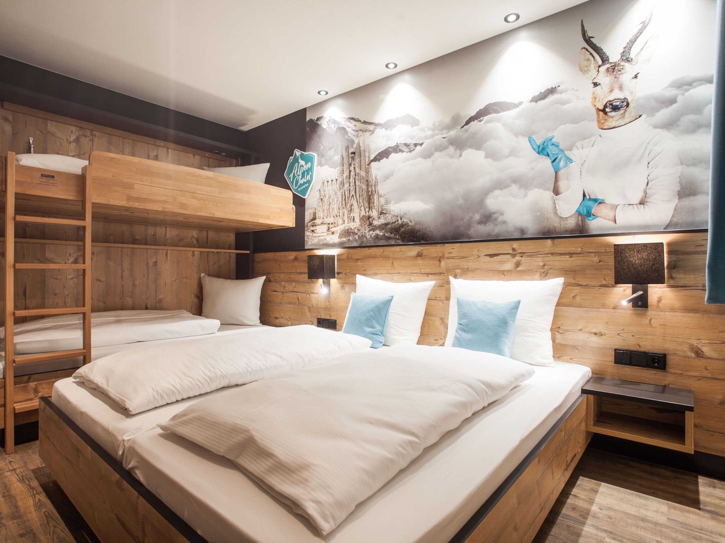 Una habitación de hotel moderna con una cama litera, cabecera de madera y un mural de un ciervo en la pared.
